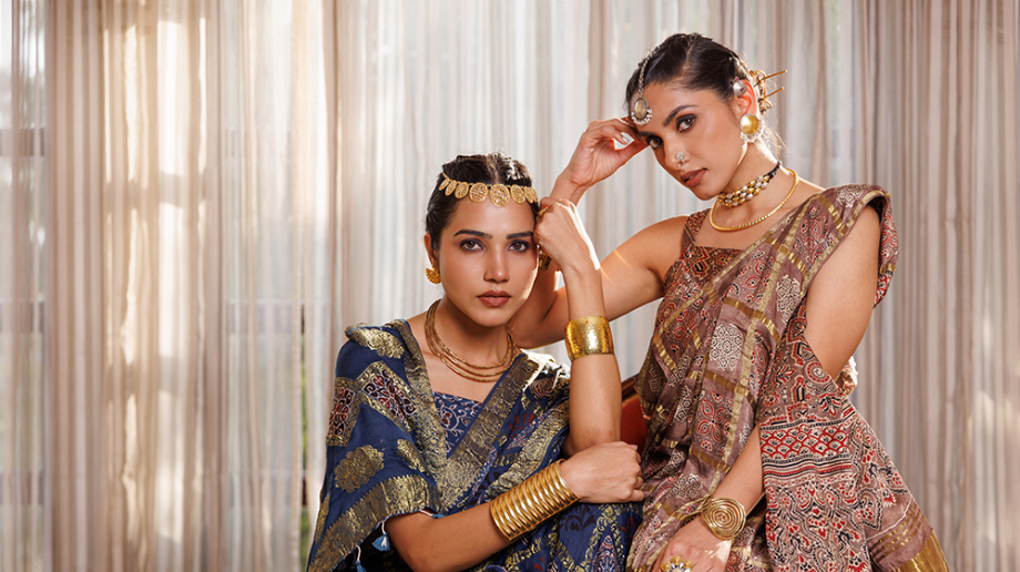 Two models wearing embellished ethnic outfits with traditional jewellery