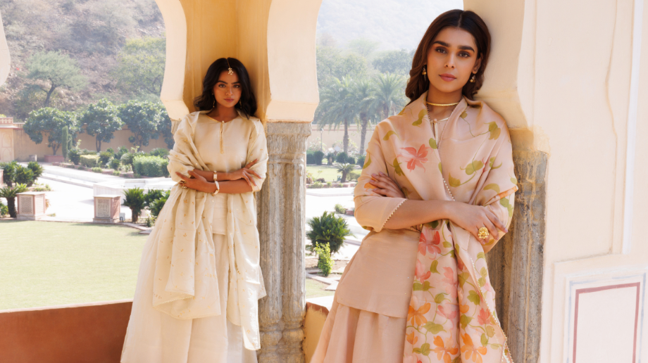 Two models wearing pastel floral ethnic outfits in an outdoor setting